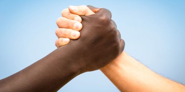 Black and white human hands in a modern handshake to show each other friendship and respect - Arm wrestling against racism